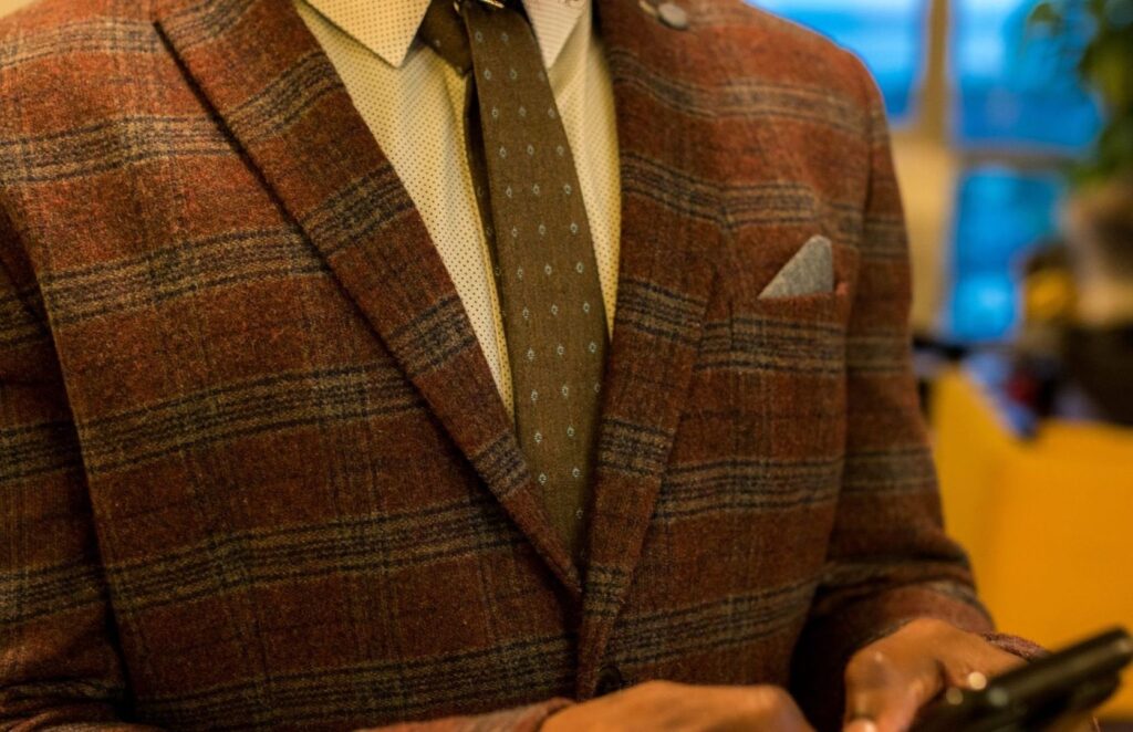 Close-up of a brown plaid tweed jacket with tie and pocket square
