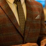 Close-up of a brown plaid tweed jacket with tie and pocket square