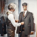 Tailor adjusting a gray flannel suit on a mannequin in a shop